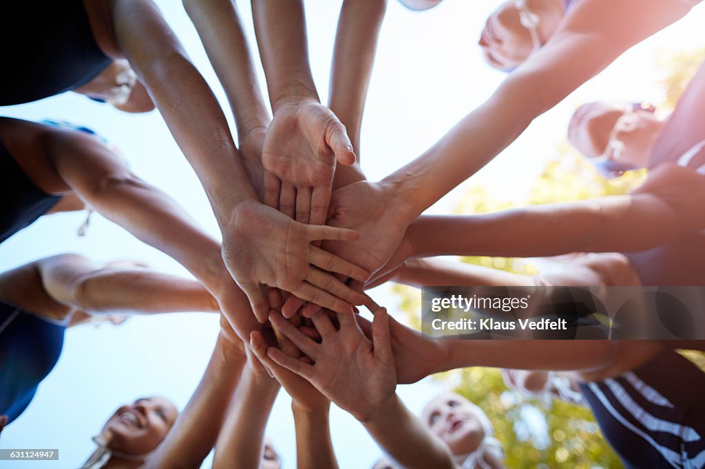 Womens waterpolo team joining hands in huddle