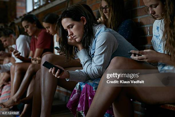 women looking at their phones in changing room - esclavitud fotografías e imágenes de stock