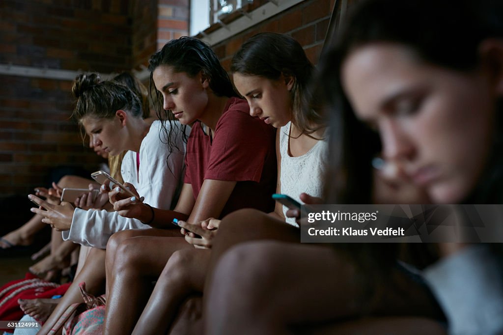 Women looking at their phones in changing room