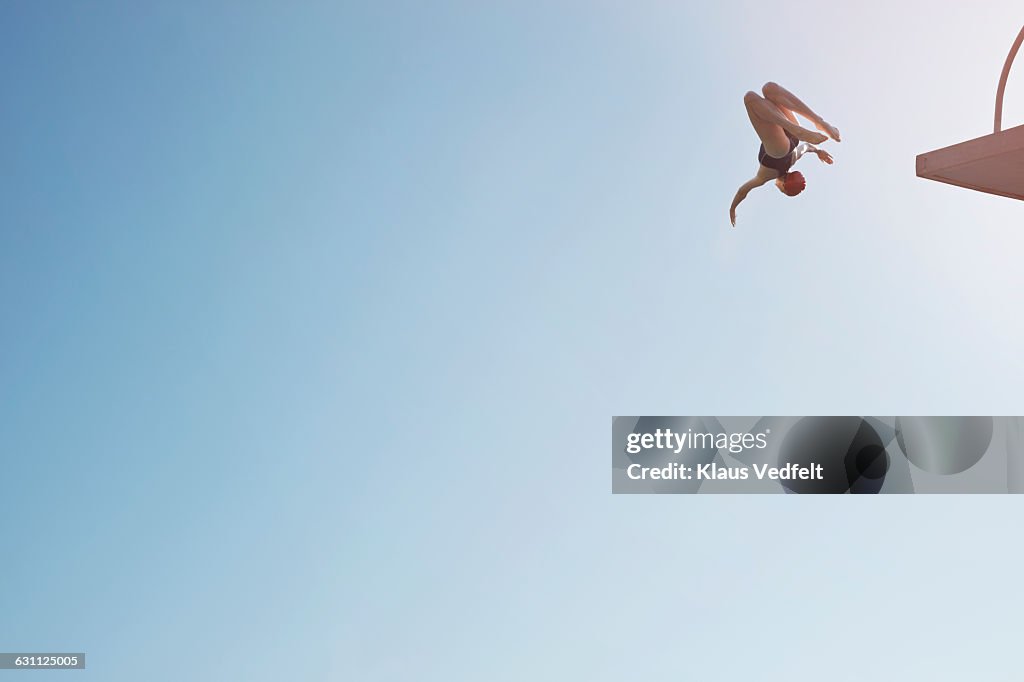Woman doing somersault from diving platform