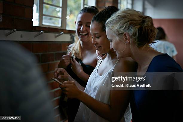 waterpolo team changing, girls looking at phone - locker room wall stock pictures, royalty-free photos & images