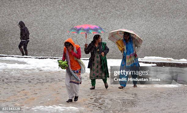 Tourists walk alongside traffic in the first snow fall of the season, in Naddi Dal Lake, on January 7 2017 in Dharamsala, India. Winter’s first heavy...