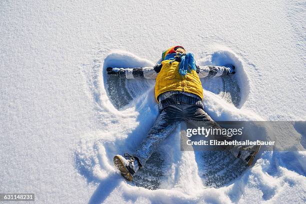 boy making a snow angel - kids playing snow stock-fotos und bilder