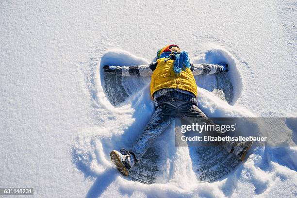 boy making a snow angel - snow fun stock pictures, royalty-free photos & images