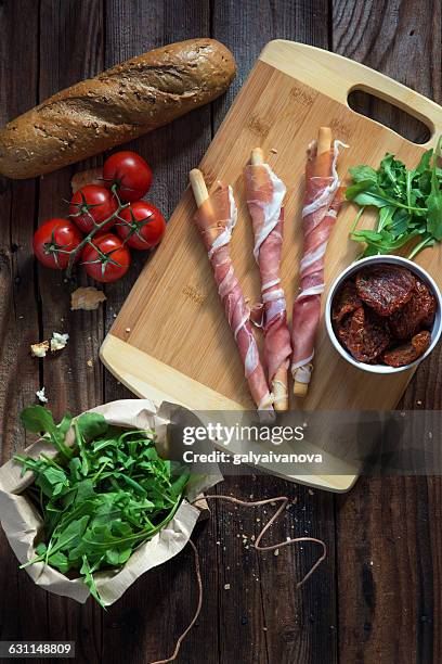 breadsticks wrapped in parma ham with tomatoes, rocket and bread - prosciutto wrapped stock pictures, royalty-free photos & images
