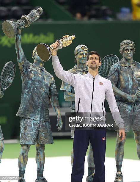 Serbia's Novak Djokovic poses with the winner's trophy after beating Britain's Andy Murray during their final tennis match at the ATP Qatar Open in...