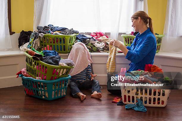 mother and young boy folding clothes and laughing together - laundry basket imagens e fotografias de stock