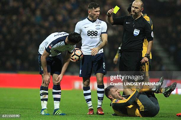 Preston's Irish defender Greg Cunningham is shown a yellow card by referee Robert Madley after a foul on Arsenal's Spanish striker Lucas Perez during...