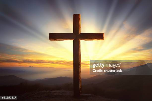 wooden cross on a hill at sunset - cross stockfoto's en -beelden