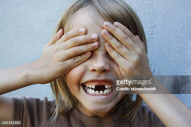 boy with gap toothed smile with hands covering eyes - hidw and seek stock pictures, royalty-free photos & images