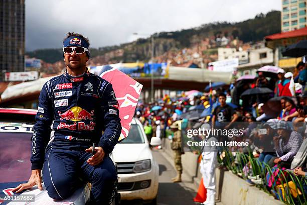 Cyril Despres of France and Peugeot Total sits on his 3008 DKR Peugeot car before driving on to the podium as fans line the streets to greet the...