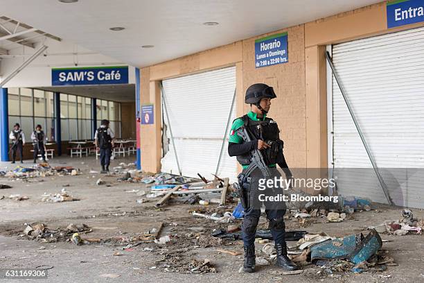 Federal police survey the damage at a Wal-Mart Stores Inc. Location after looting in Veracruz City, Mexico, on Saturday, Jan. 7, 2017. Mexico's...