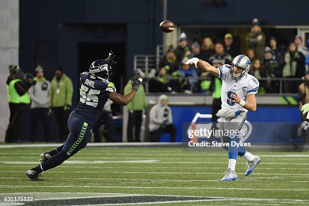 Matthew Stafford of the Detroit Lions throws a pass during the first half as he is pressured by Cliff Avril of the Seattle Seahawks in the NFC Wild...