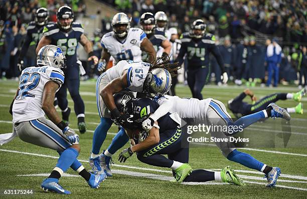 Jermaine Kearse of the Seattle Seahawks is tackled by Josh Bynes and Nevin Lawson of the Detroit Lions during the first half of the NFC Wild Card...