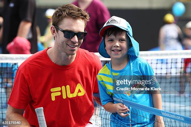 Australian tennis player John Peers poses for a photo with a young player after playing tennis with them at Memorial Drive Tennis court during the...