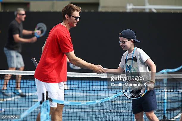 Australian tennis player John Peers shakes hands with a young player after playing tennis with them at Memorial Drive Tennis court during the 2017...
