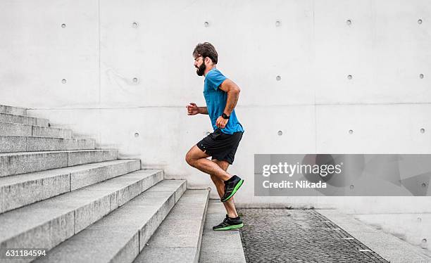 sporty man running up steps in urban setting - stappen stockfoto's en -beelden
