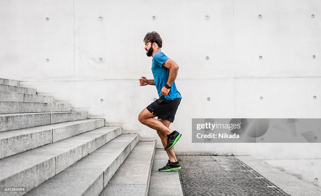 Sporty man running up steps in urban setting