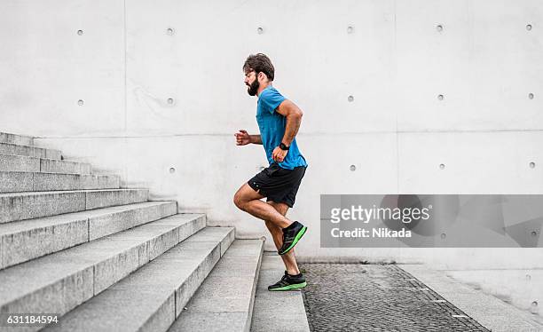 sporty man running up steps in urban setting - sportswear stock pictures, royalty-free photos & images