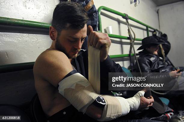 Professional bareback rider RC Landingham of Hat Creek, Alberta, Canada, tapes up his arm before the bareback riding finals of the "Colorado vs The...