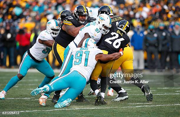 Le'Veon Bell of the Pittsburgh Steelers is wrapped up for a tackle by Cameron Wake of the Miami Dolphins and Jordan Phillips in the first quarter...