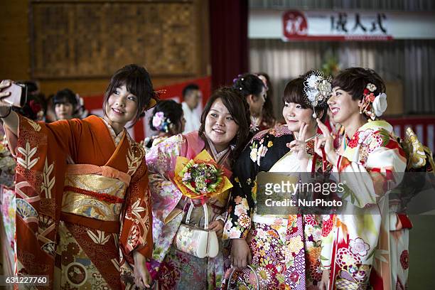 New adults in kimonos takes photos after attending a Coming of Age Day celebration ceremony in Shuri Junior High School in Okinawa, Japan on January...