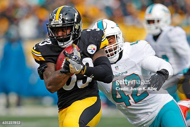 Fitzgerald Toussaint of the Pittsburgh Steelers rushes against Spencer Paysinger of the Miami Dolphins in the first half during the Wild Card Playoff...