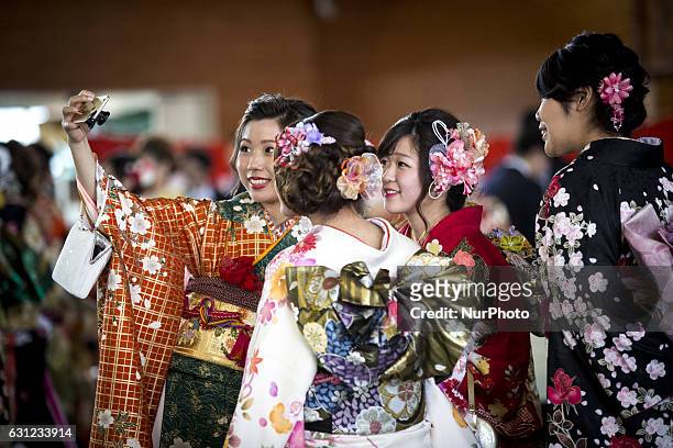 New adults in kimonos takes selfies after attending a Coming of Age Day celebration ceremony in Shuri Junior High School in Okinawa, Japan on January...