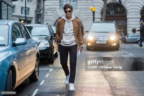 Oliver Cheshire wearing a grey hoody, Ray Ban sunglasses, brown jacket during London Fashion Week Men's January 2017 collections at KTZ on January 8,...