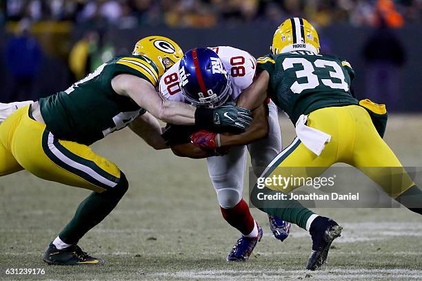 Jake Ryan and Micah Hyde of the Green Bay Packers tackle Victor Cruz of the New York Giants in the second quarter during the NFC Wild Card game at...