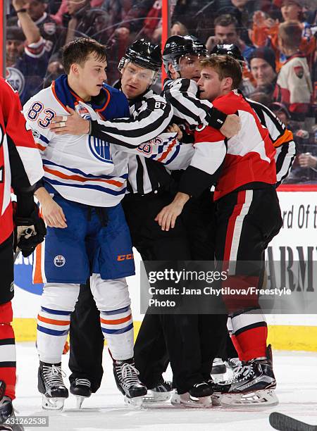 Chris Wideman of the Ottawa Senators and Matthew Benning the Edmonton Oilers are separated by linesman Devin Berg and linesman Brad Kovachik after...