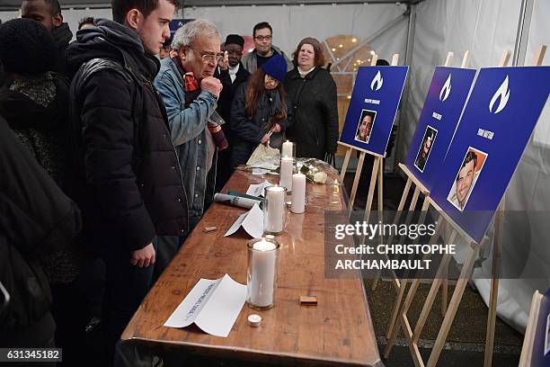 People stand in front of candles and pictures of people killed in the deadly attack against the Hyper Cacher supermarket in 2015, during a ceremony...