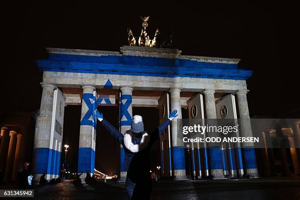 Woman strikes a pose in front of the Brandenburg Gate with the Israeli flag projected onto in Berlin, on January 9, 2017 to pay tribute to the...