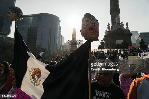 Demonstrators hold signs and a Mexican flag with masks in the likeness of Enrique Pena Nieto, Mexico's president, during a protest against the...