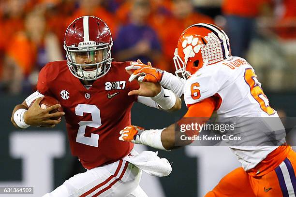 Quarterback Jalen Hurts of the Alabama Crimson Tide runs with the ball as linebacker Dorian O'Daniel of the Clemson Tigers attempts to tackle him...