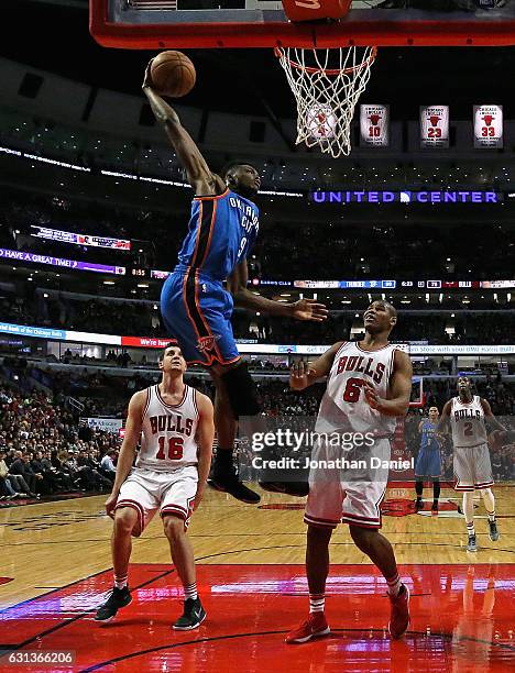 Jerami Grant of the Oklahoma City Thunder dunks over Paul Zipser and Cristiano Felicio of the Chicago Bulls at the United Center on January 9, 2017...