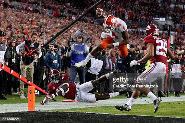 Quarterback Deshaun Watson of the Clemson Tigers is stopped short of the goal line by defensive back Ronnie Harrison of the Alabama Crimson Tide...