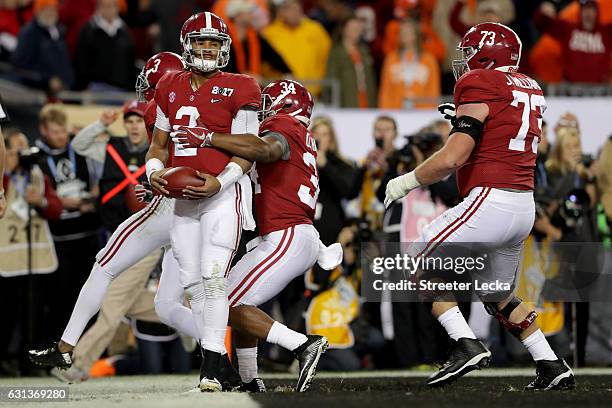 Quarterback Jalen Hurts of the Alabama Crimson Tide celebrates with teammates after rushing for a 30-yard touchdown during the fourth quarter against...