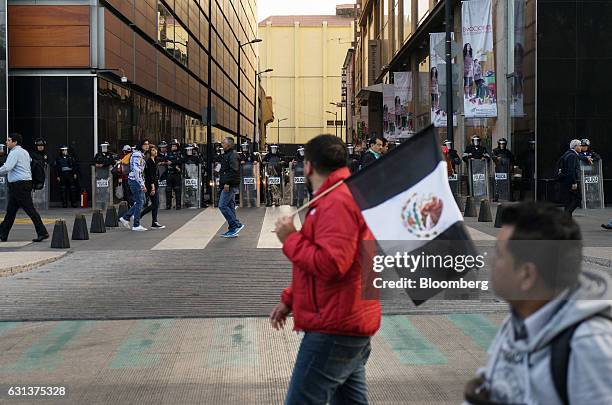 Demonstrators march past police officers in riot gear during a protest against the gasoline price hike in Mexico City, Mexico, on Monday, Jan. 9,...