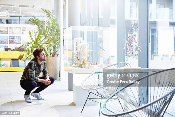 designer contemplates an architects model. - man crouching stock pictures, royalty-free photos & images