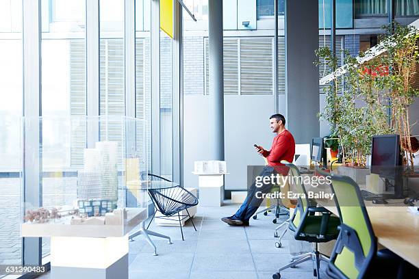 designer relaxing and looking out of window. - vanguardista fotografías e imágenes de stock