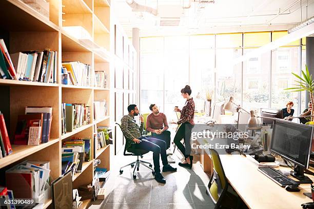 creative coworkers chatting over ideas in office - creative desk stock-fotos und bilder