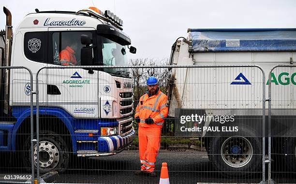 Security staff stands between gravel trucks as workers construct an access road at the Preston New Road site where Energy firm Cuadrilla are setting...