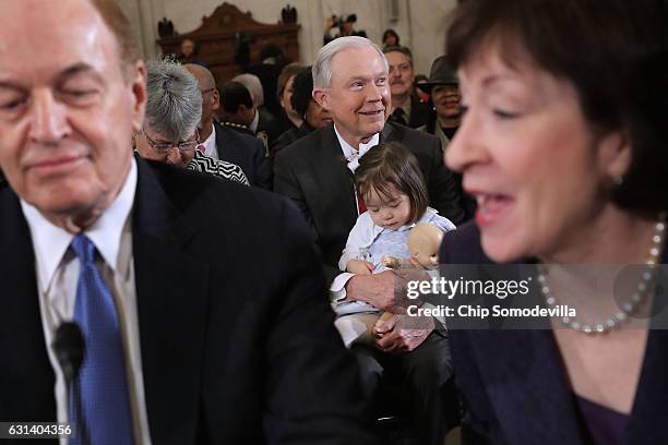 Framed by Sen. Richard Shelby and Sen. Susan Collins , Sen. Jeff Sessions holds one of his granddaughters before the start of his confirmation...