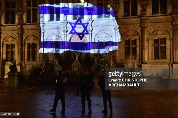 French CRS anti-riot police officers patrol as the Israeli flag is projected onto the facade of the Hotel de Ville in Paris on the night of January...