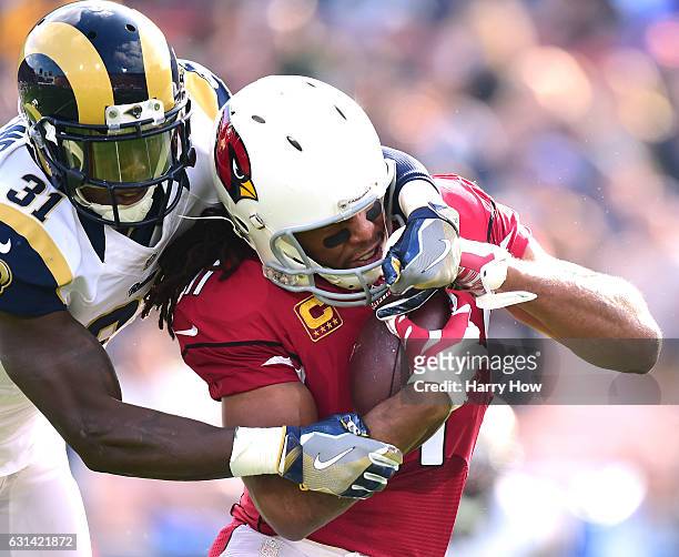 Larry Fitzgerald of the Arizona Cardinals is tackled by Maurice Alexander of the Los Angeles Rams after his catch at Los Angeles Memorial Coliseum on...