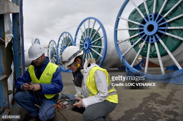 Workers check with ultrasound a blade of an offshore floating wind turbine prototype, on January 10, 2017 in Saint-Nazaire, western France.