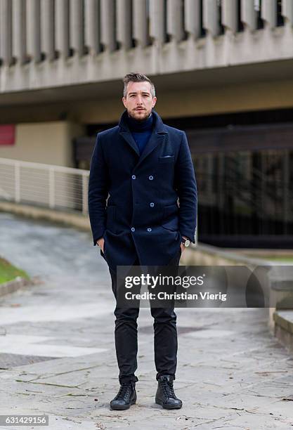 Alessandro Amici is wearing a navy double-breasted coat, black pants, black boots on January 10, 2017 in Florence, Italy.