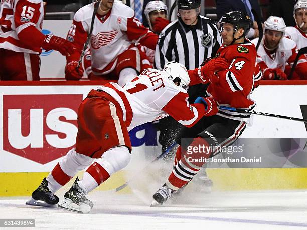 Xavier Ouellet of the Detroit Red Wings hits Richard Panik of the Chicago Blackhawks at the United Center on January 10, 2017 in Chicago, Illinois....