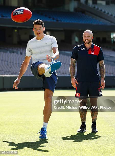 Canadian tennis player Milos Raonic and Melbourne AFL captain Nathan Jones kick the football during a Melbourne Demons AFL media opportunity at...